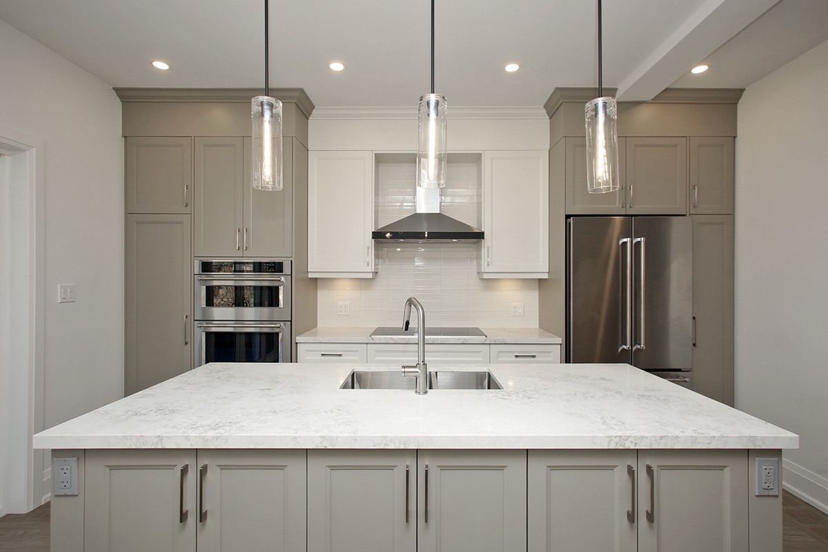 Bright transitional kitchen in Alderwood with a large quartz island, warm grey cabinets, and stainless appliances.