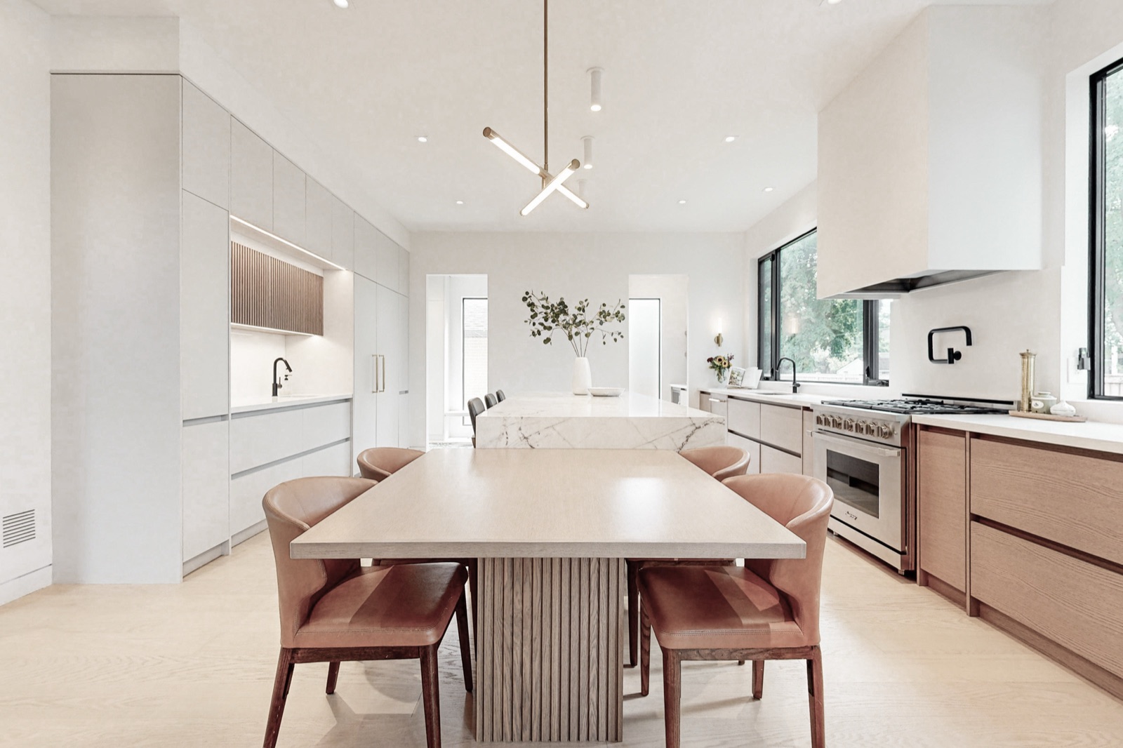 Open-concept kitchen designed and built by Waterfront, with an oversized marble island and a sculptural brass chandelier.