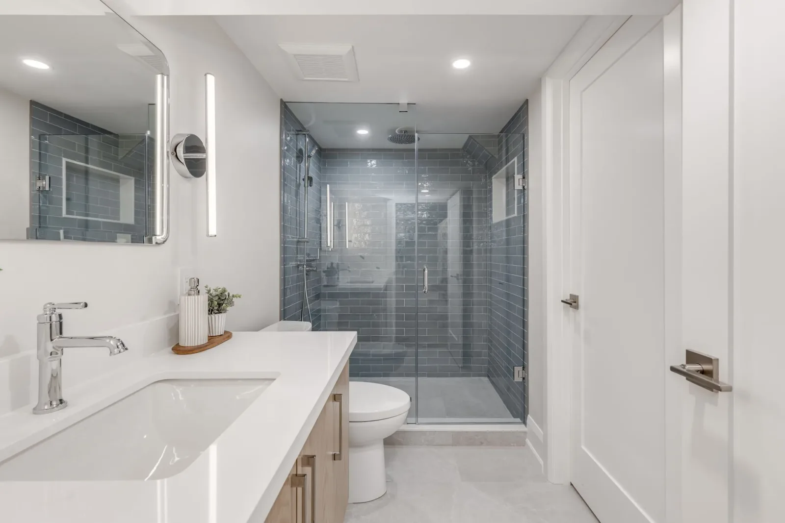Basement apartment bathroom with a tiled glass shower, countertop, and vanity, finished by Waterfront Home Improvements in Toronto