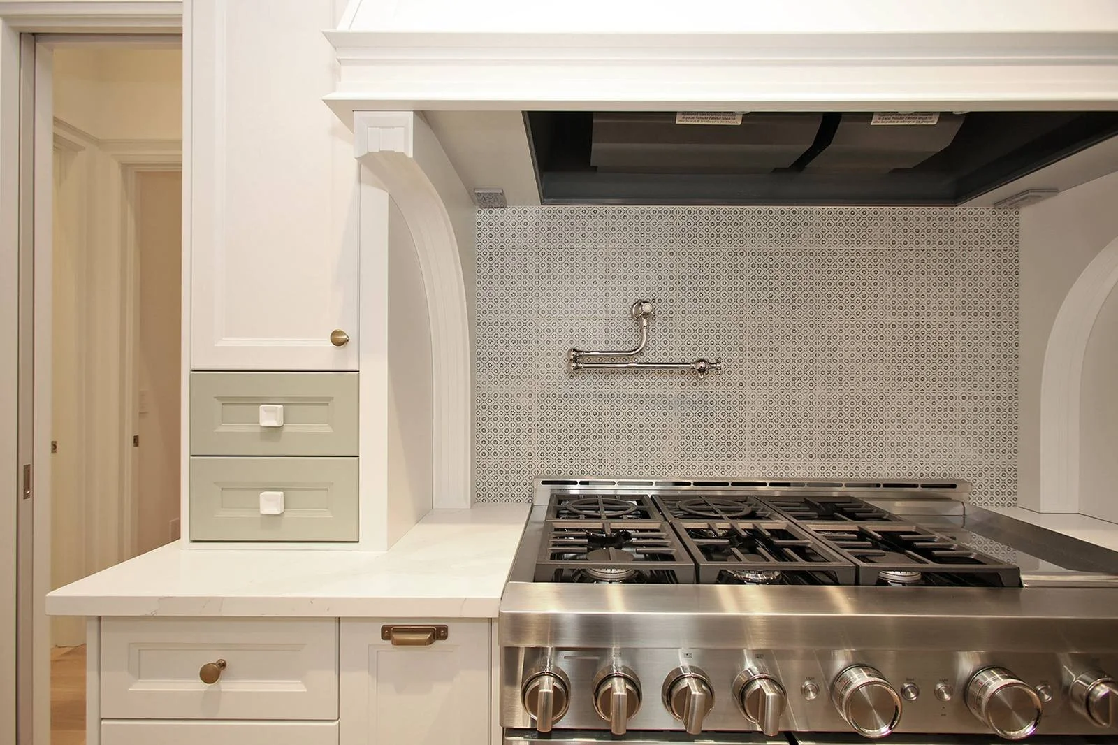 Kitchen range alcove with a grey mosaic tile backsplash, pot filler, and professional gas range