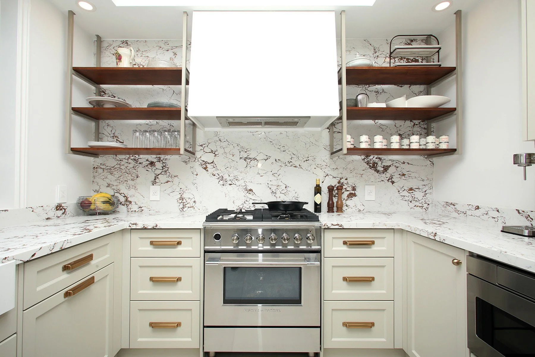U-shaped kitchen with a dramatic veined stone backsplash, open shelving, and a gas range under a white hood