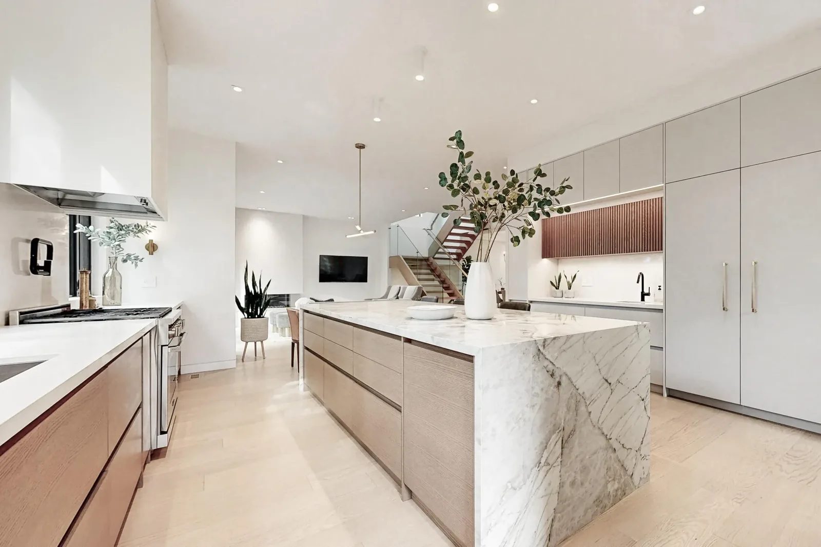 Bright modern kitchen with a matte white prep run, calacatta marble island and dining table extension, and a bench nook at the end of the hall.