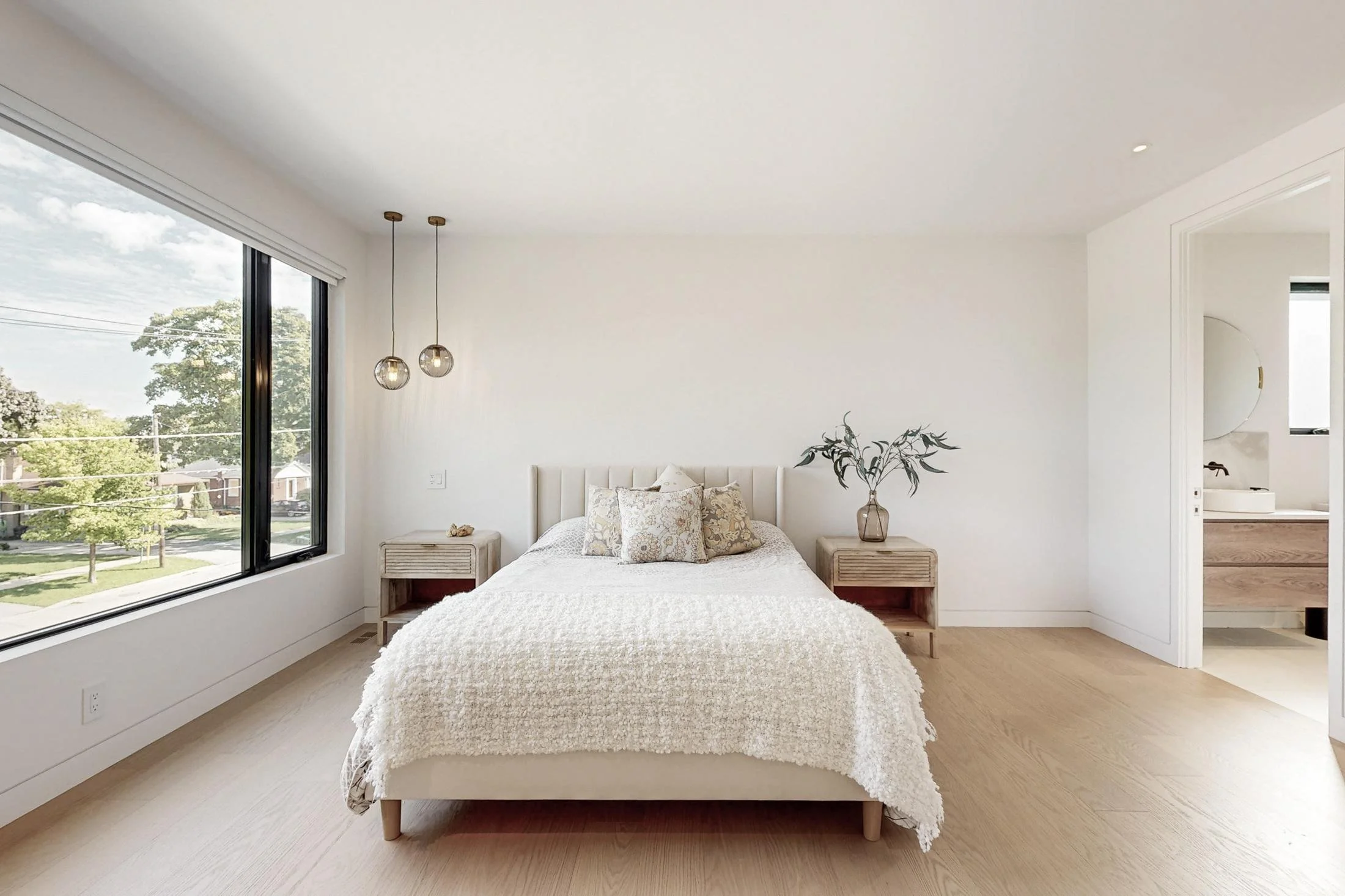 Calm bedroom with a light wood bed, glass pendant lights, and a black-framed window.