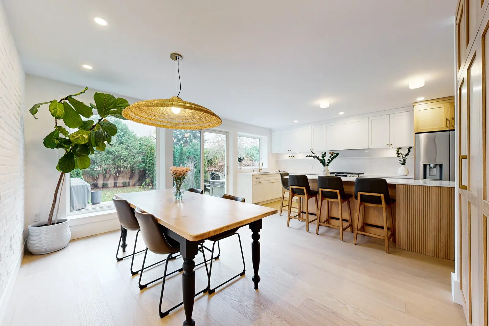 Bright open-concept kitchen and dining area with white cabinetry after an interior reconfiguration.