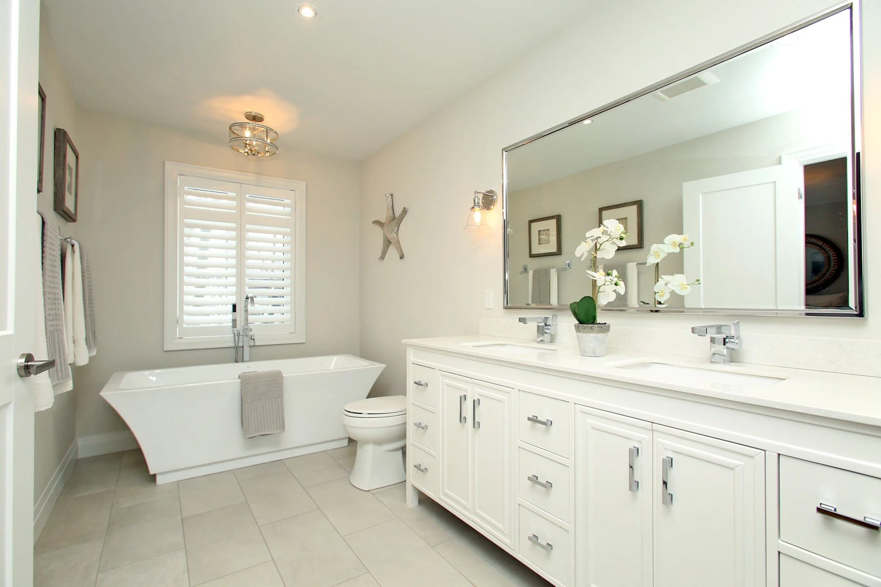 Bright renovated bathroom with a double vanity, freestanding tub and soft neutral colour palette.