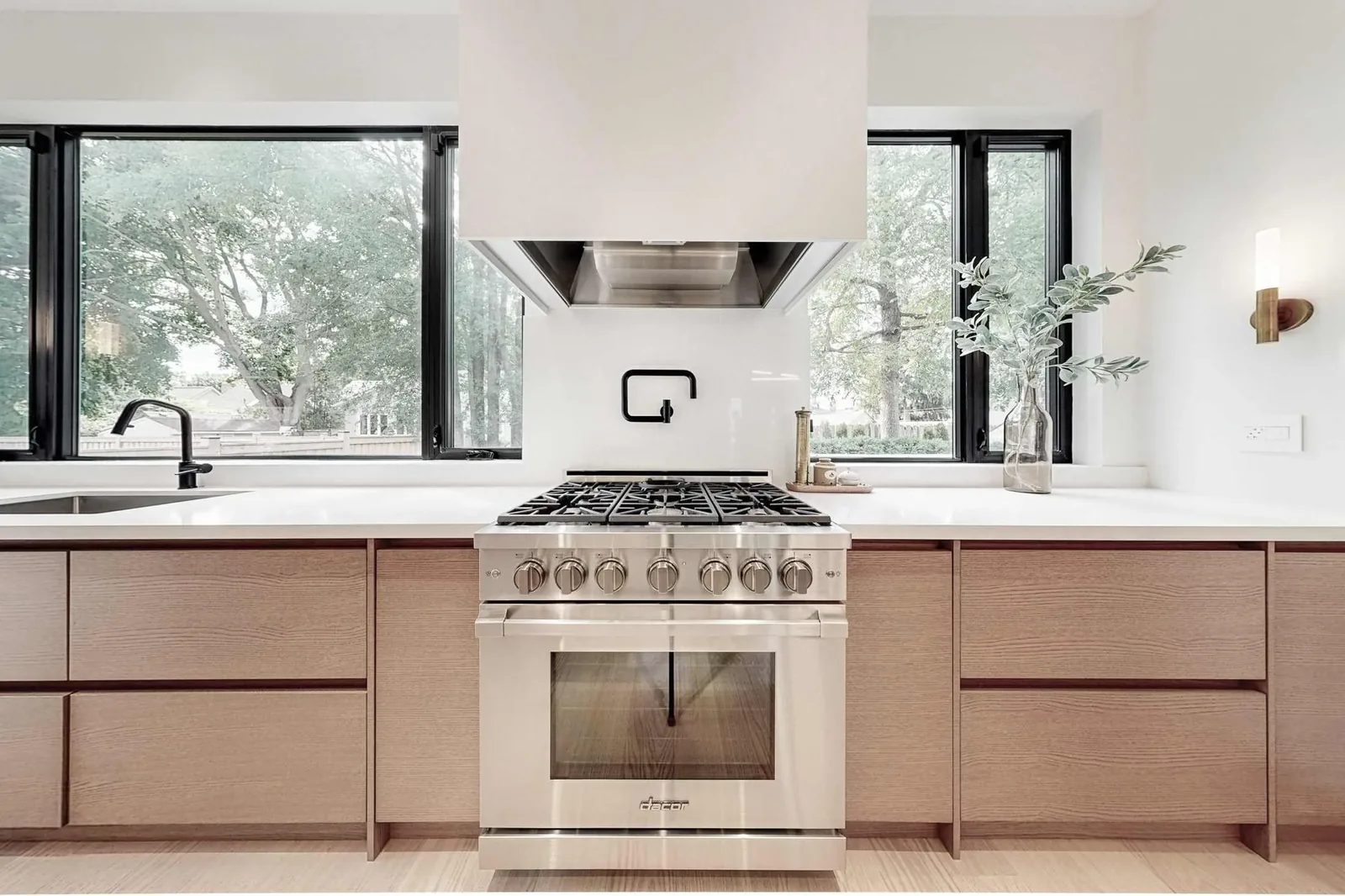 Gas cooktop in the foreground looks across an open-concept living room with a linear fireplace.