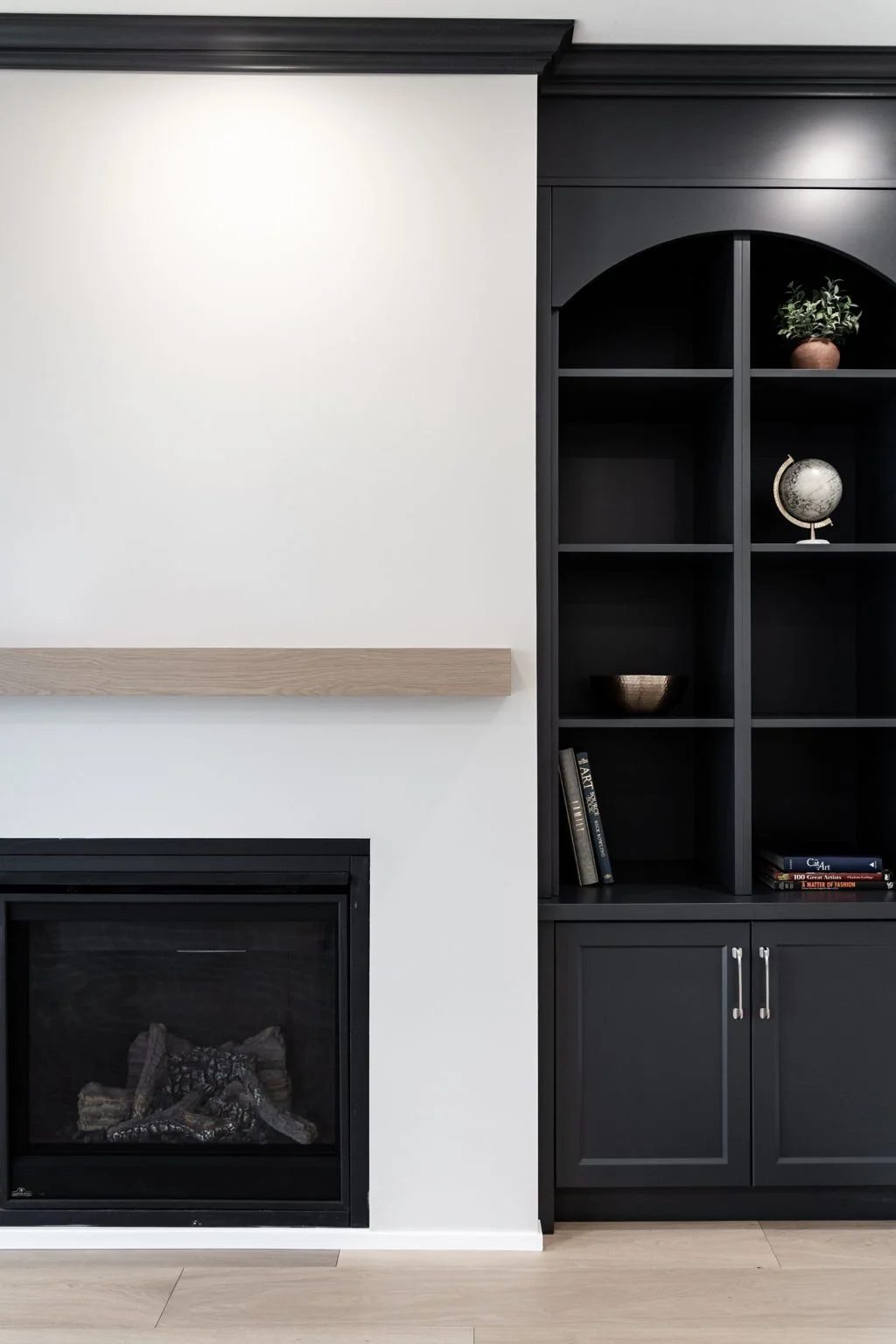 Warm white fireplace wall with a natural oak mantel and matte black built-ins for organised living.