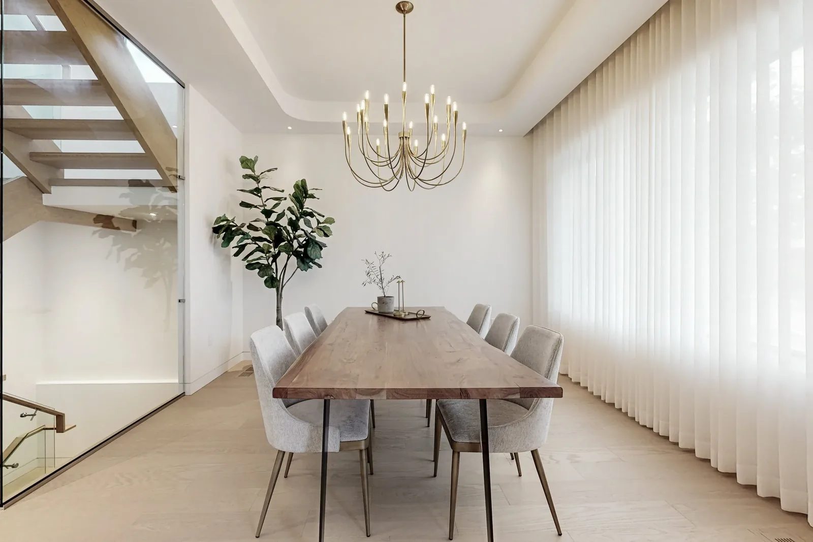 Dining room viewed from the stair side with a wall of linen sheers softening the brass candelabra chandelier.