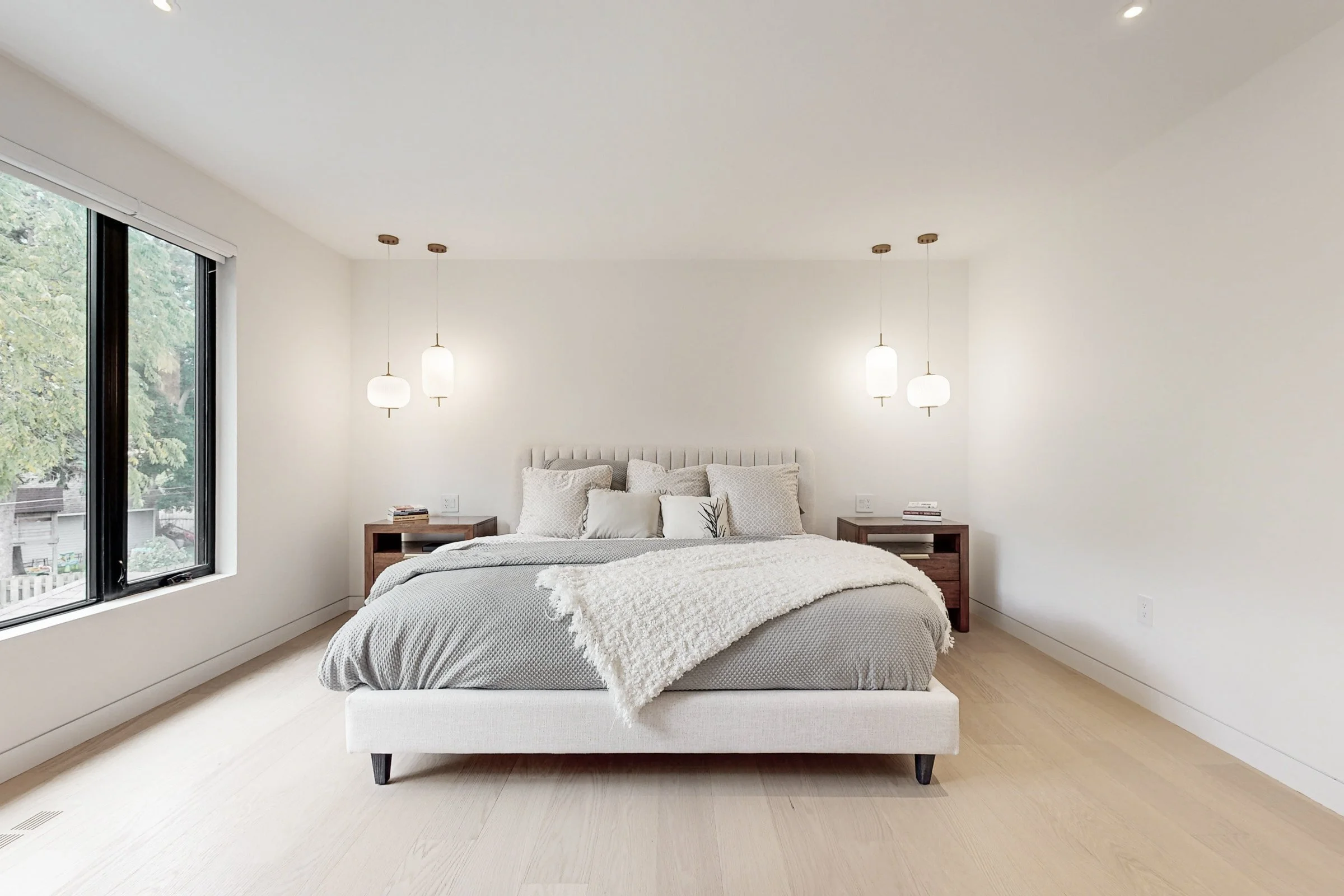Principal bedroom with channel upholstered bed framed by matched walnut nightstands and pendant pairs.