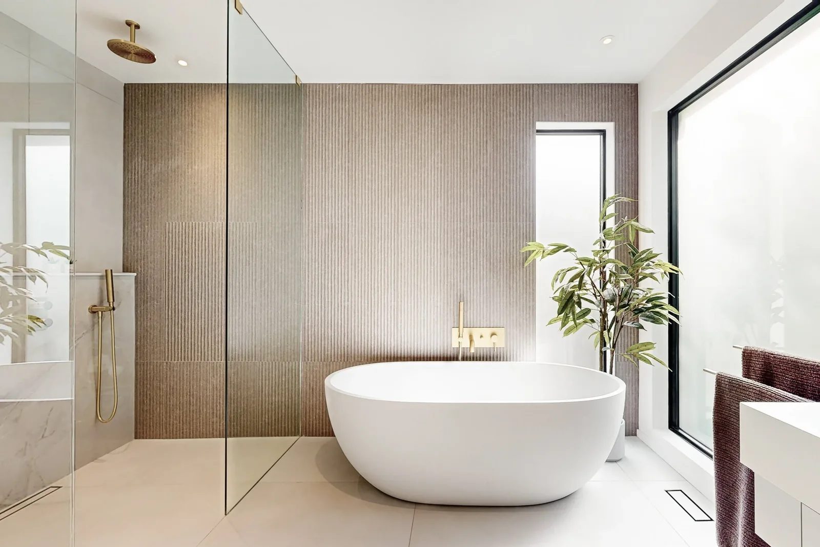 Spa ensuite centred on a freestanding tub with fluted stone accent wall and brushed gold filler.