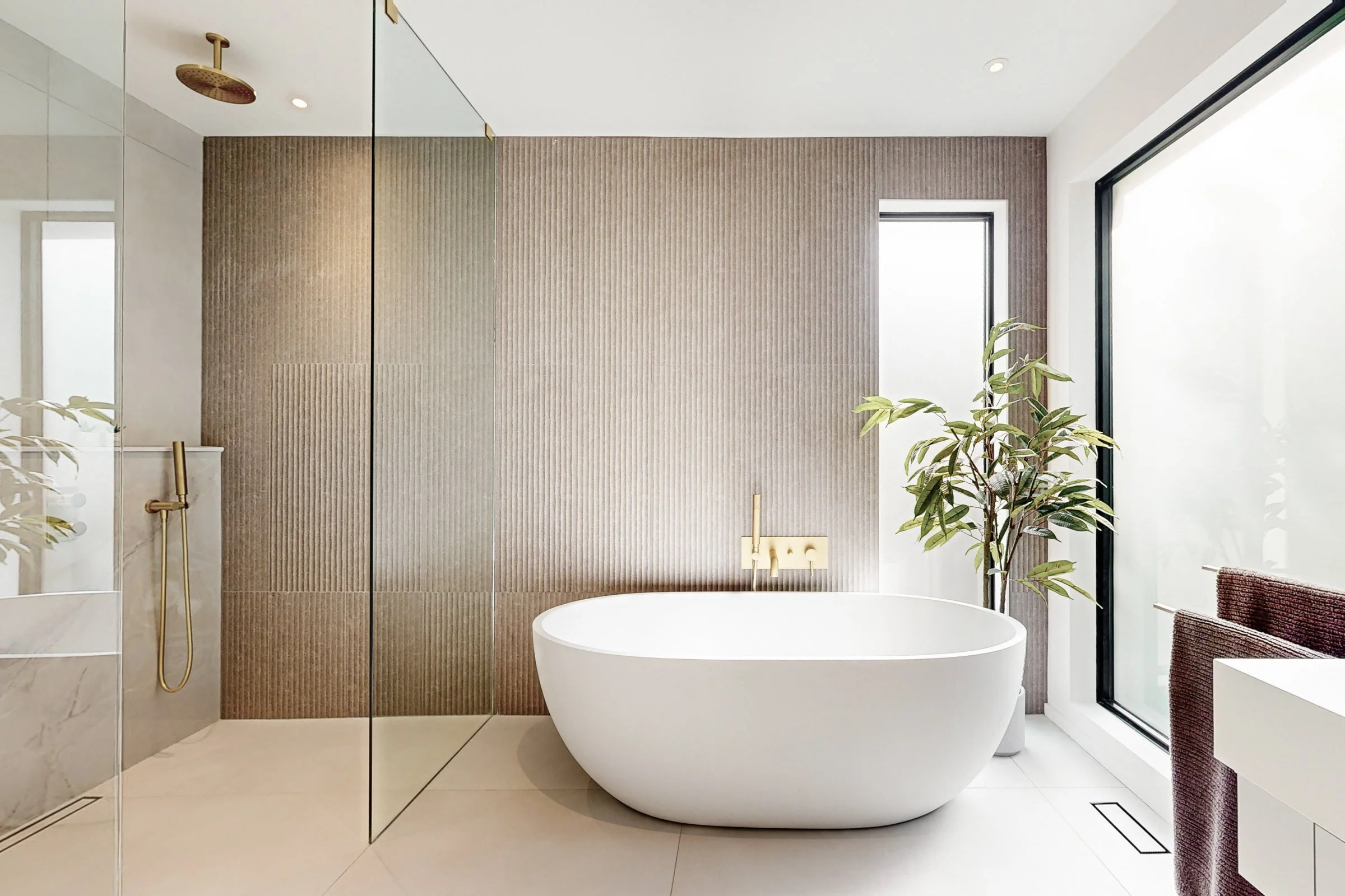 Spa ensuite centred on a freestanding tub with fluted stone accent wall and brushed gold filler.