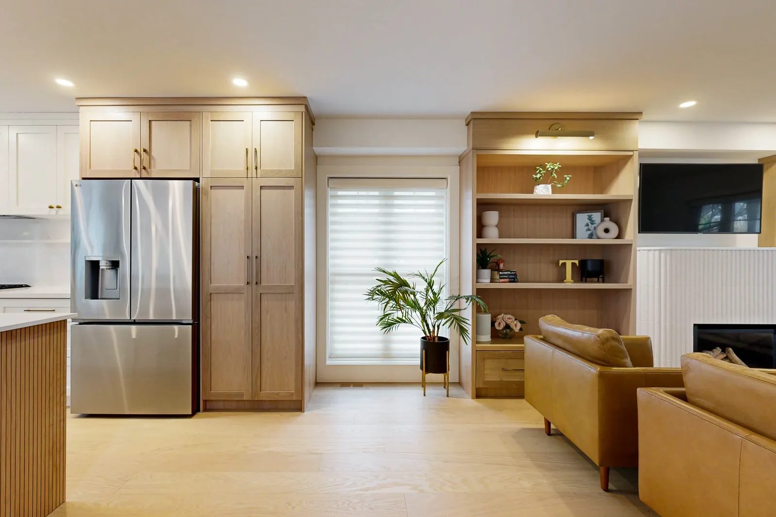 Open concept kitchen and living area with oak cabinetry, built-in shelves, and a bright rear door.