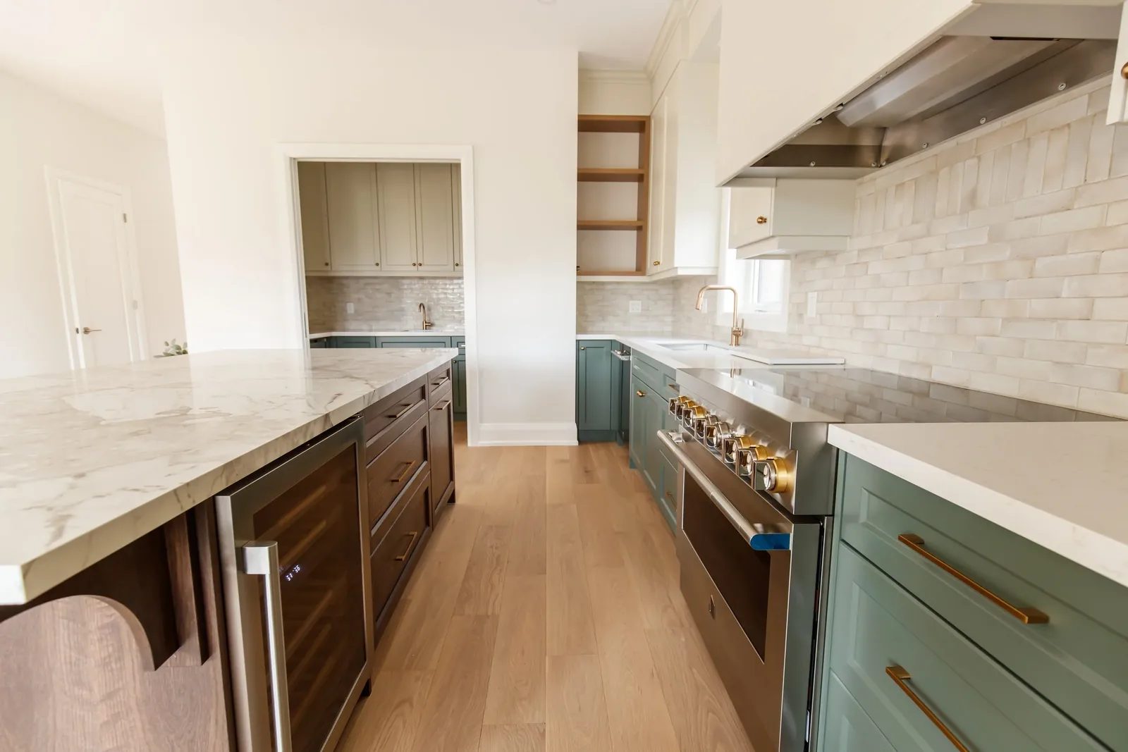 Finished two-tone kitchen viewed across a walnut marble-topped island with arched reeded end.