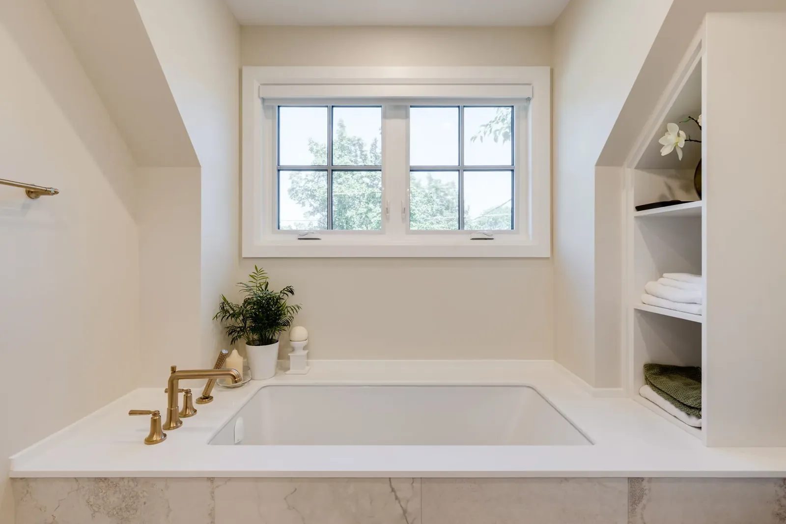 Main bathroom with a reeded walnut double vanity, a stone counter with an integrated backsplash, brass tapware and a frameless glass shower in green herringbone tile.