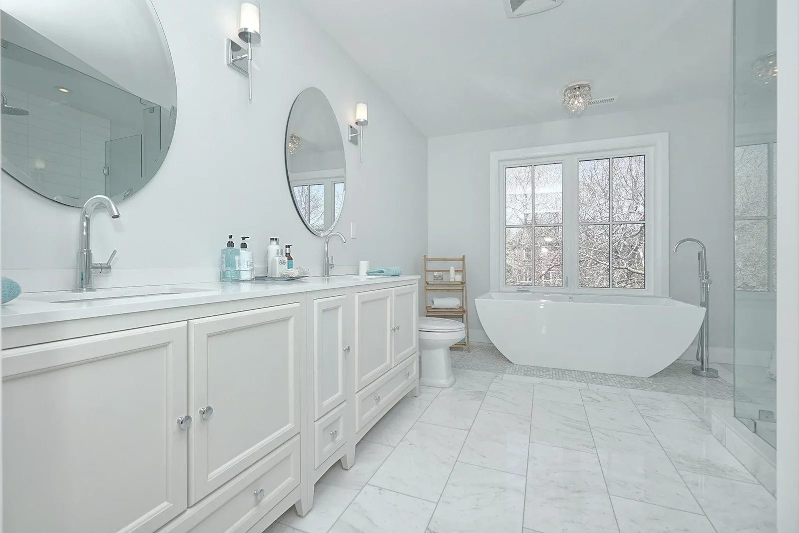 Primary bathroom with a white double vanity, freestanding tub, and glass shower in the Sophisticated Coastal home.