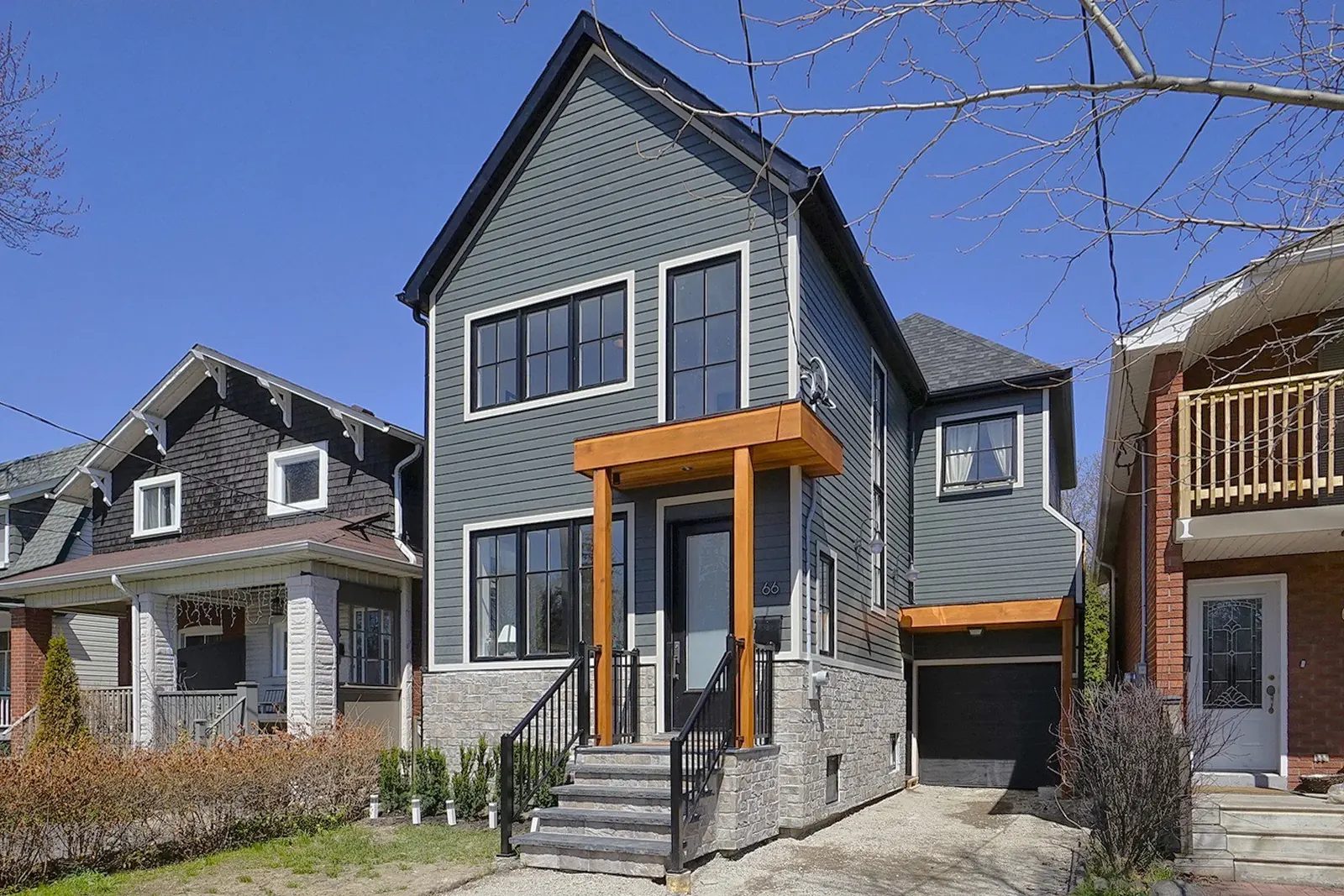 Finished grey detached home with wood porch details and stone veneer on a Toronto neighbourhood lot.