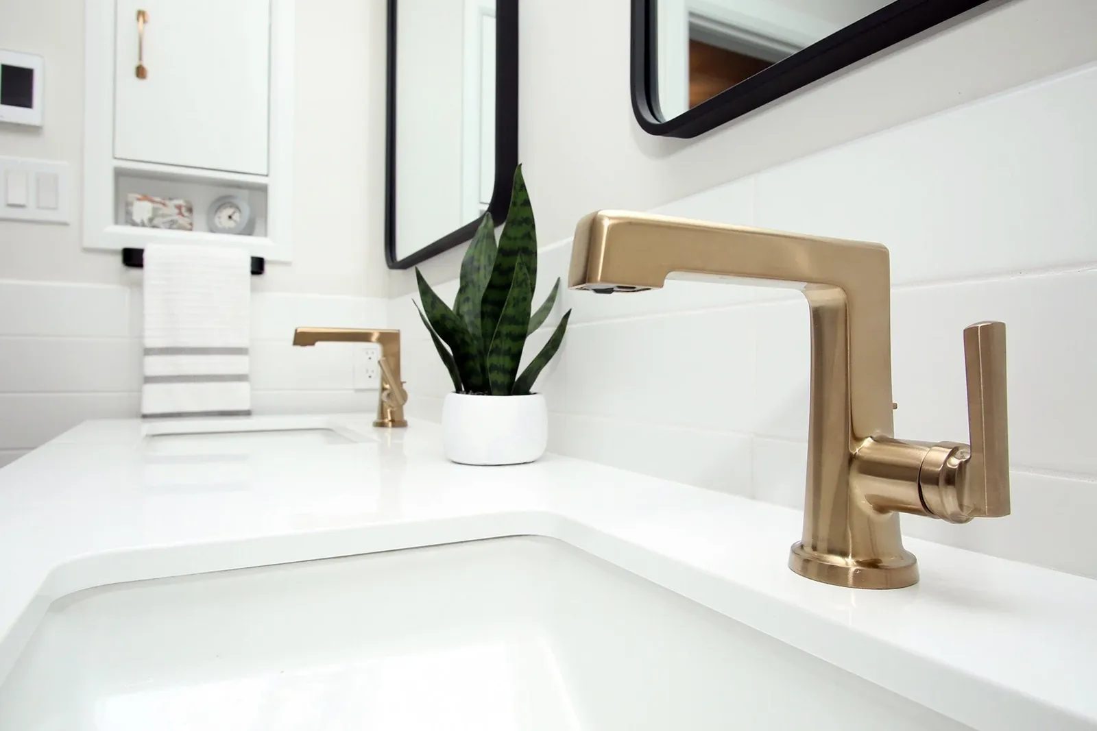 Brushed gold faucet on a white quartz vanity with a snake plant, Timeless Elegance project