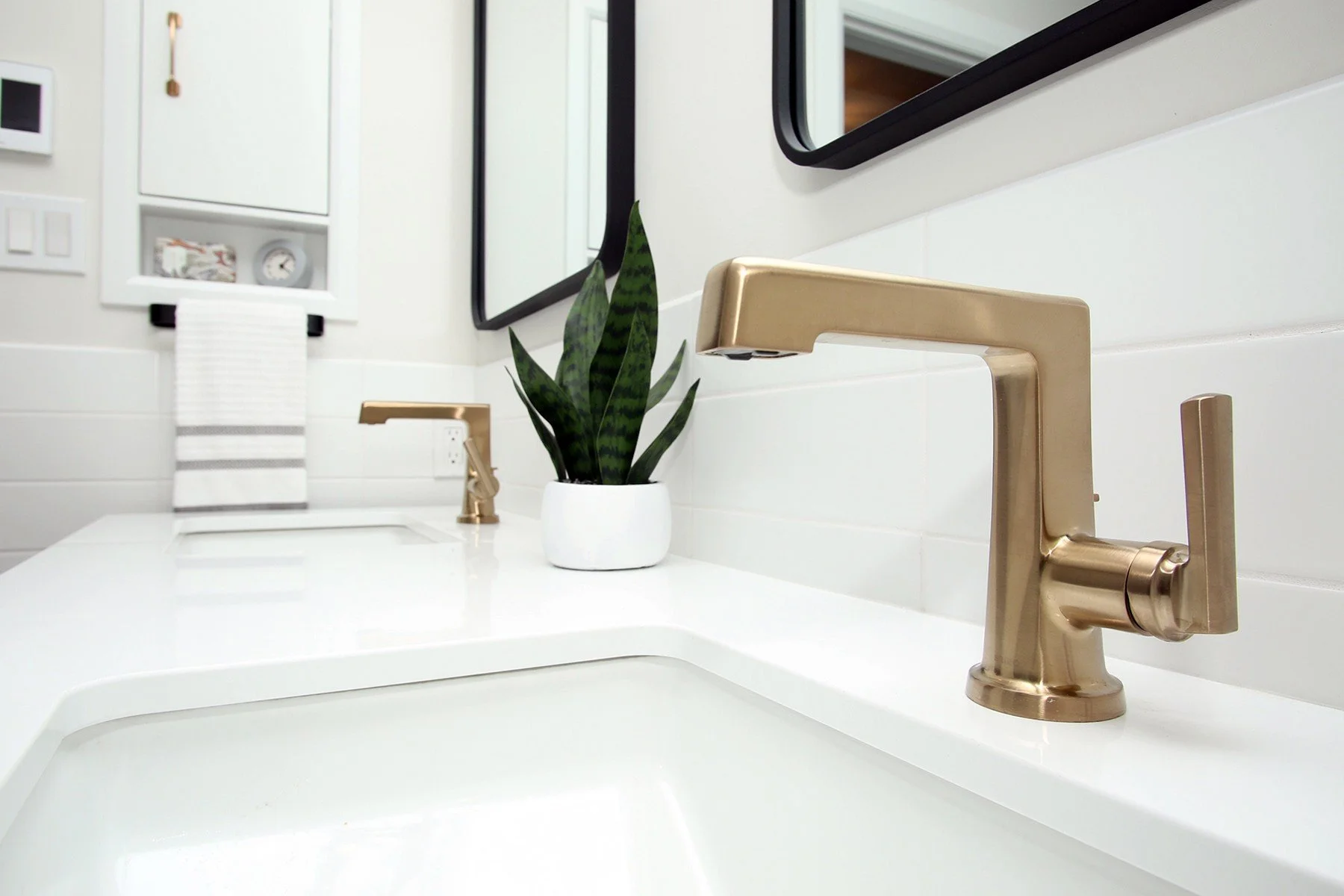 Brushed gold faucet on a white quartz vanity with a snake plant, Timeless Elegance project