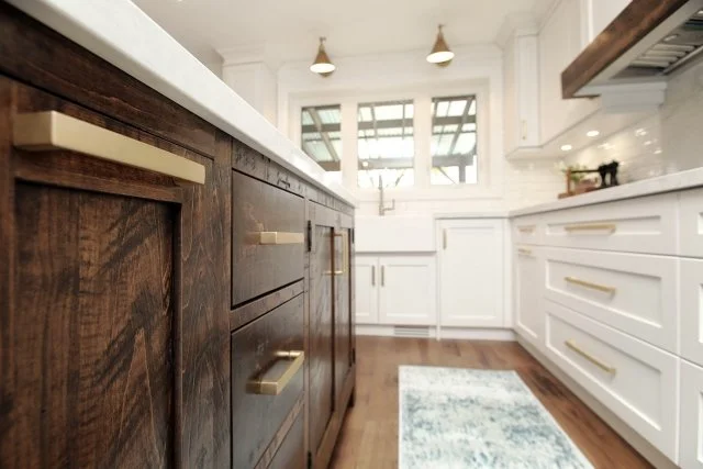 Rustic wood island with brass pulls facing white kitchen cabinetry, Timeless Elegance project