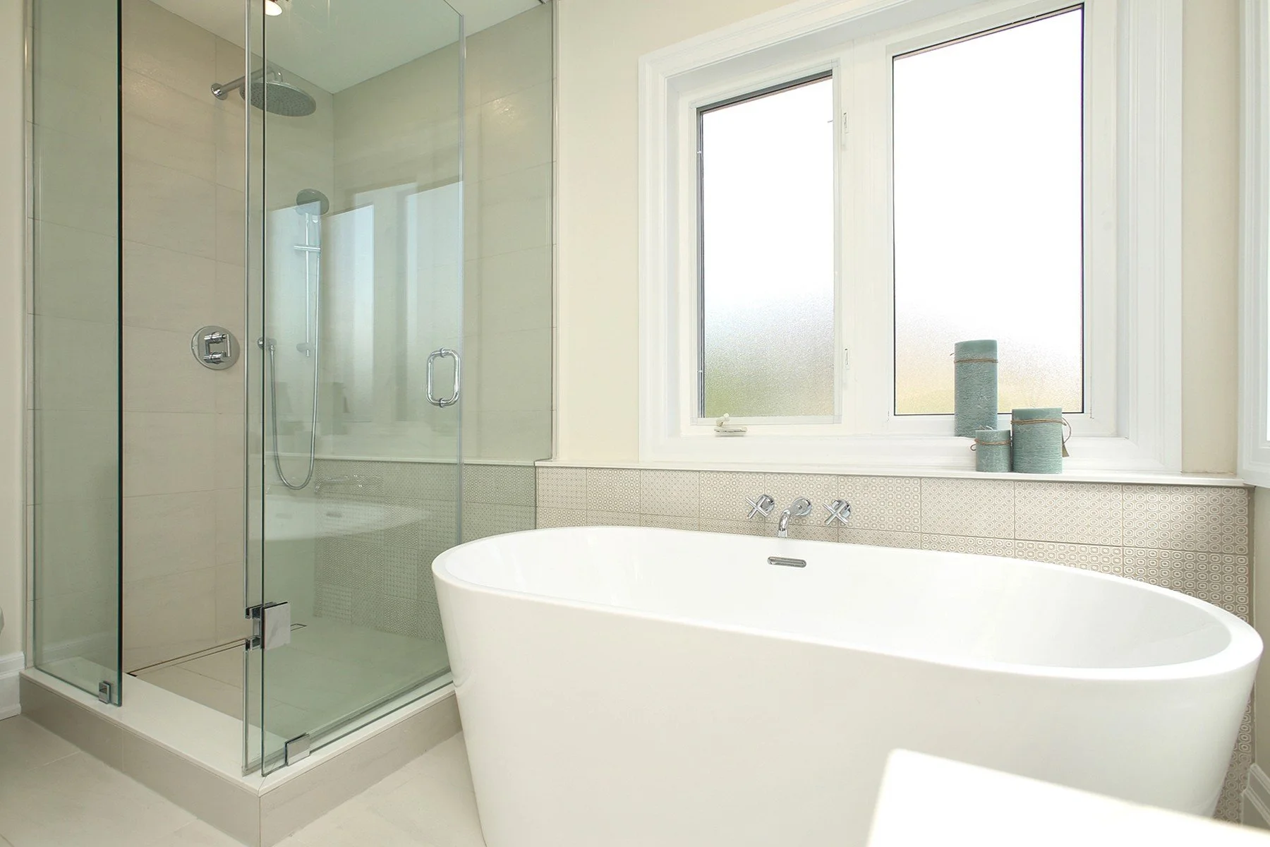 Bright renovated bathroom with a freestanding tub, glass shower, and a warm white colour palette.
