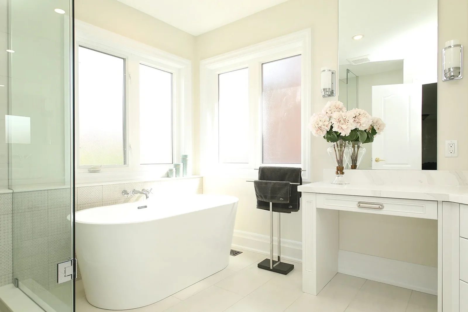 Bright bathroom renovation with a freestanding tub, glass shower, white vanity and soft neutral finishes.