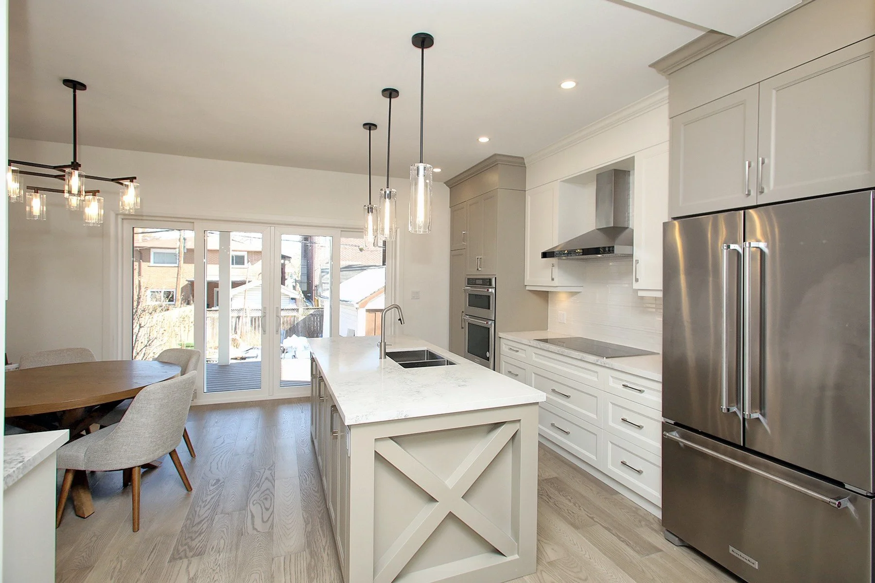 Open kitchen and dining with a live edge table, X panel island, French doors, and stainless appliances.