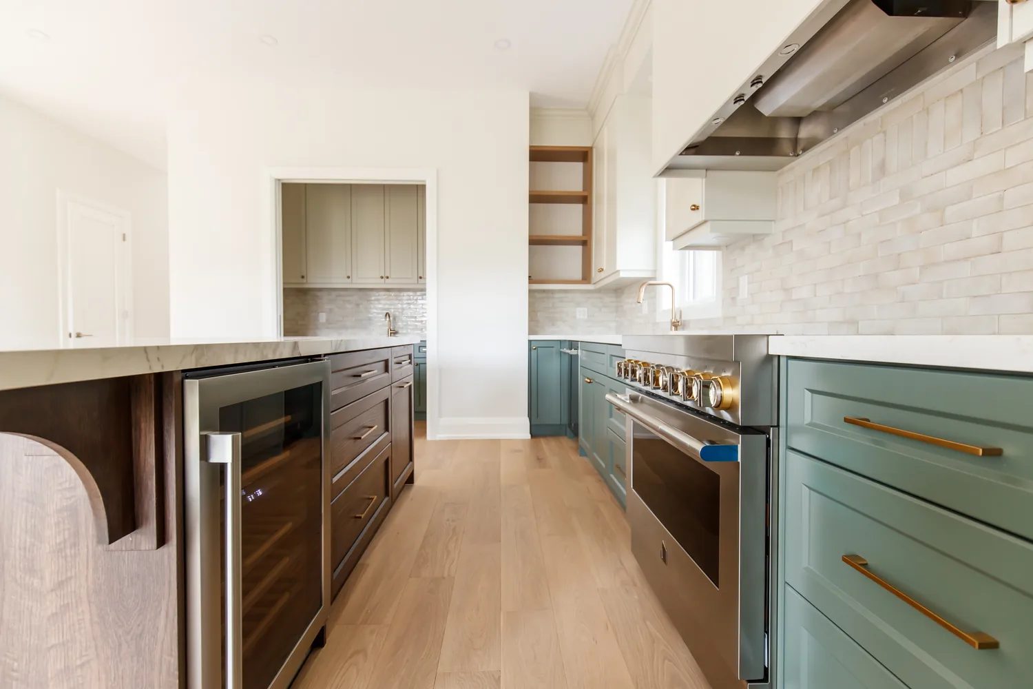 Finished chef kitchen with a walnut island, arched reeded end panel, sage green cabinets, and a marble backsplash.