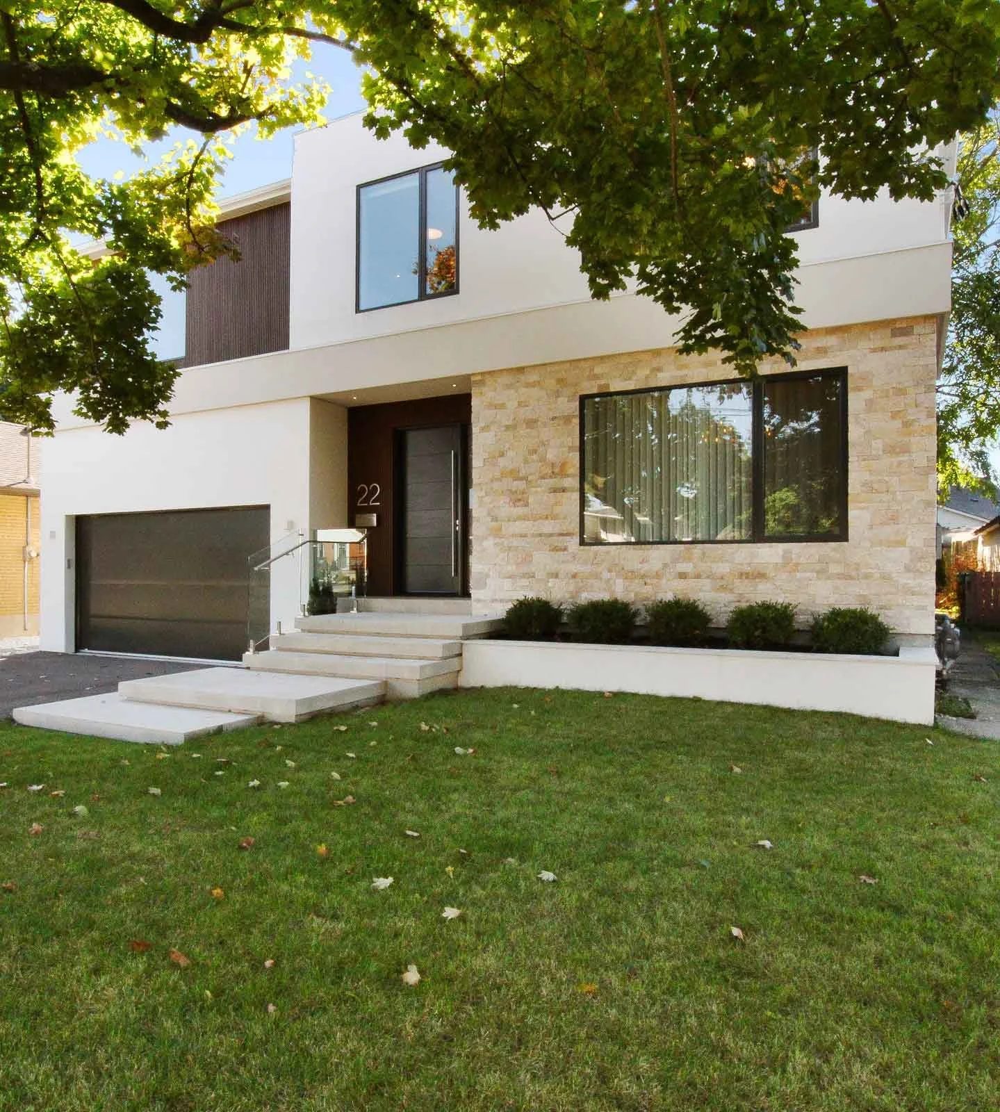 A contemporary two-storey custom home with white stucco and natural stone cladding on the front elevation