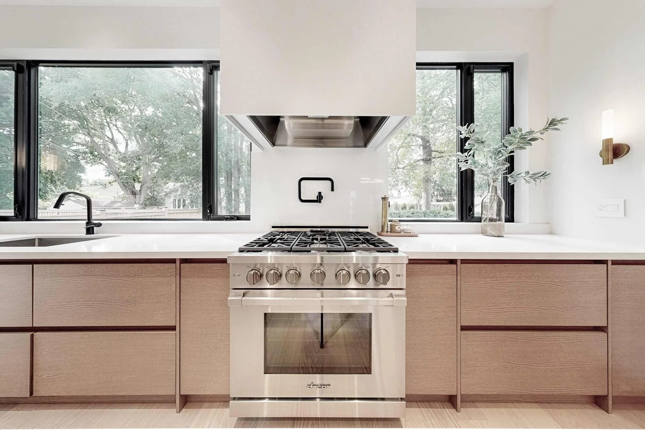 Gas cooktop in the foreground looks across an open-concept living room with a linear fireplace.