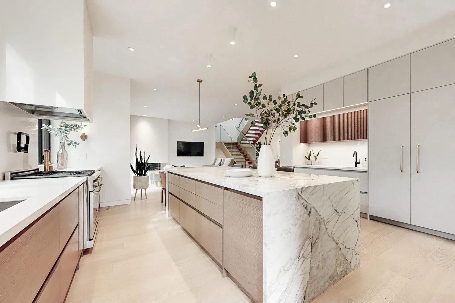 Open kitchen with marble island and brass details in a finished Etobicoke custom build.