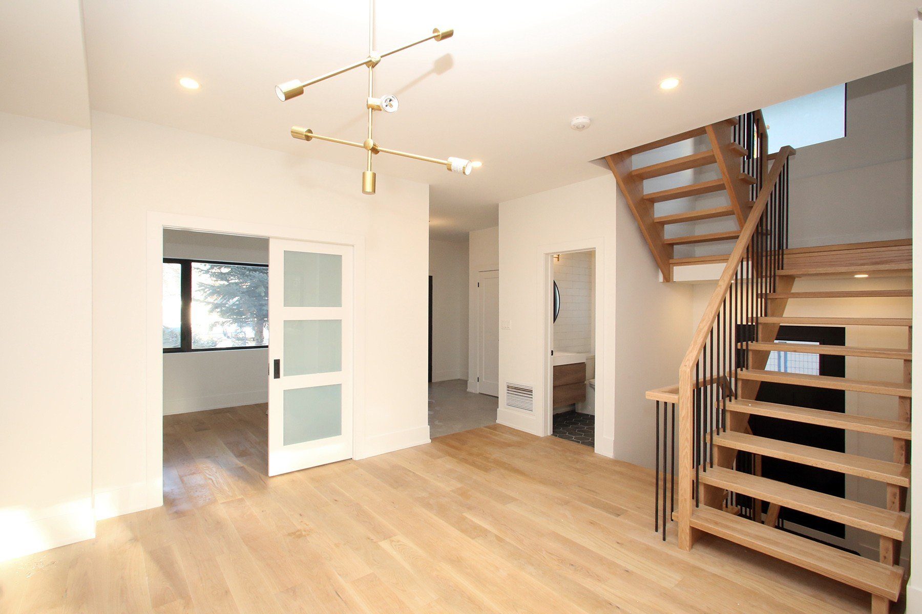 Finished open living area with natural oak stairs, warm white walls, and frosted glass sliding doors.